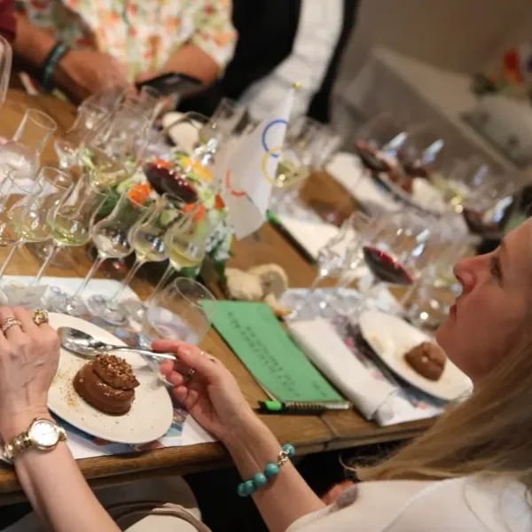 Une femme goûte un dessert devant une table avec plusieurs verres de vin et des petits plats