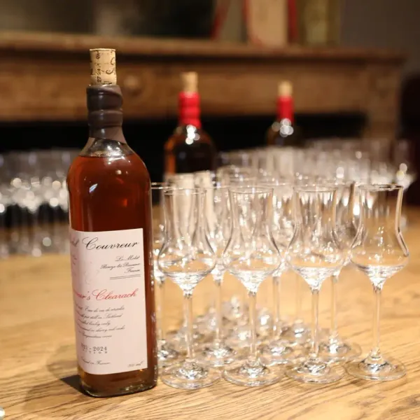 Une bouteille de whisky avec des verres à dégustation alignés sur une table en bois