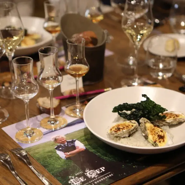Table dressée avec des verres à vin, des plats contenant des huîtres et des accompagnements, et des sets de table publicitaires