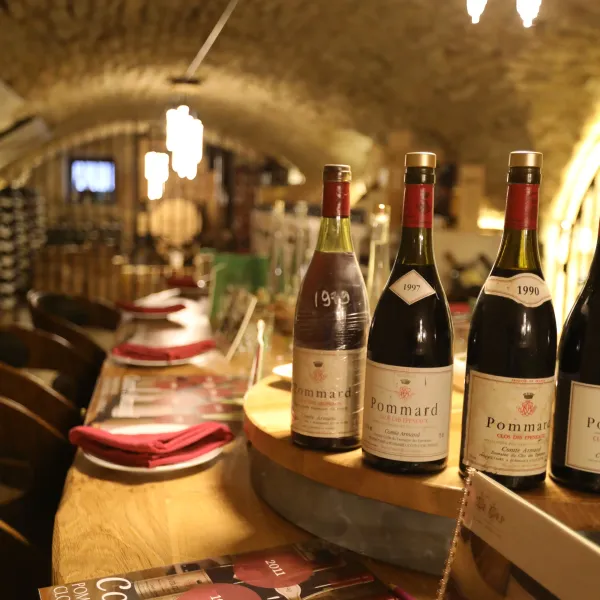 Bouteilles de vin alignées sur des étagères en bois avec des étiquettes indiquant différentes années de récolte