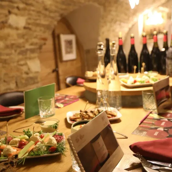 Table dressée avec des plats, des bouteilles de vin et des verres dans un cadre rustique avec des murs en pierre