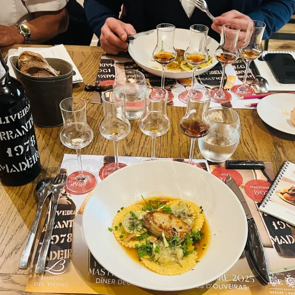 Une table avec des verres à vin, une bouteille, des plats de nourriture et des brochures