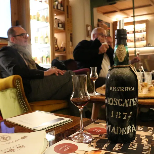 Un homme assis dans un restaurant avec une bouteille de vin "Reserva Moscatel 1875" sur la table devant lui