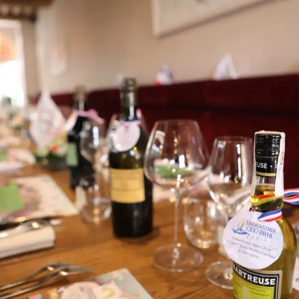 Bouteille de Chartreuse et verres à vin sur une table avec des brochures et des menus